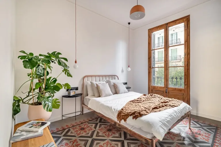Dormitorio luminoso con cama de metal y plantas
