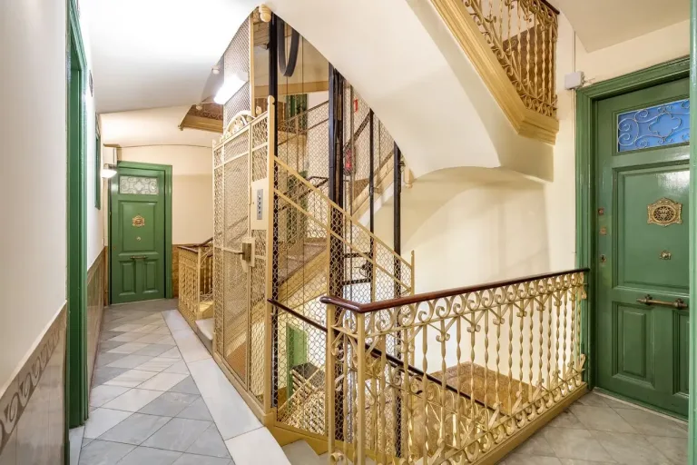Elegante vestíbulo con ascensor de época y detalles ornamentales