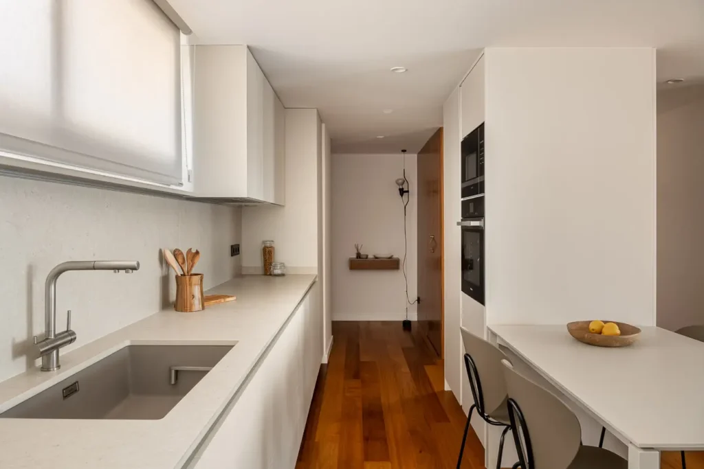cocina alargada con muebles blancos y luz natural