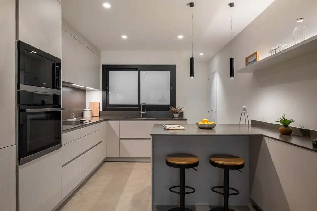 cocina moderna con encimeras grises y taburetes de bar negros