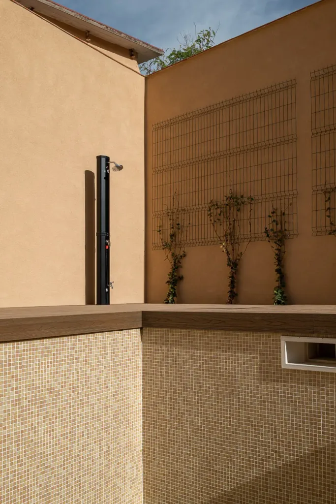 detalle de piscina con revestimiento de mosaico y ducha exterior