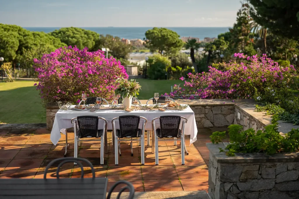 mesa puesta en terraza con flores y mar de fondo