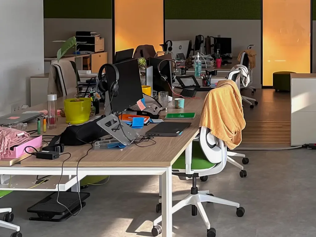 oficina con escritorios sillas y computadoras desordenada (1)