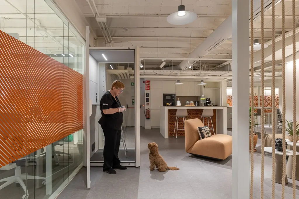 persona interactuando con perro en oficina con cabina telefonica
