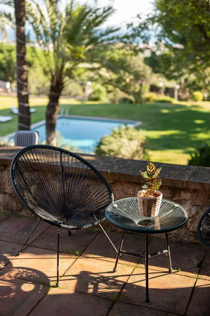 terraza con sillas mesa y piscina de fondo