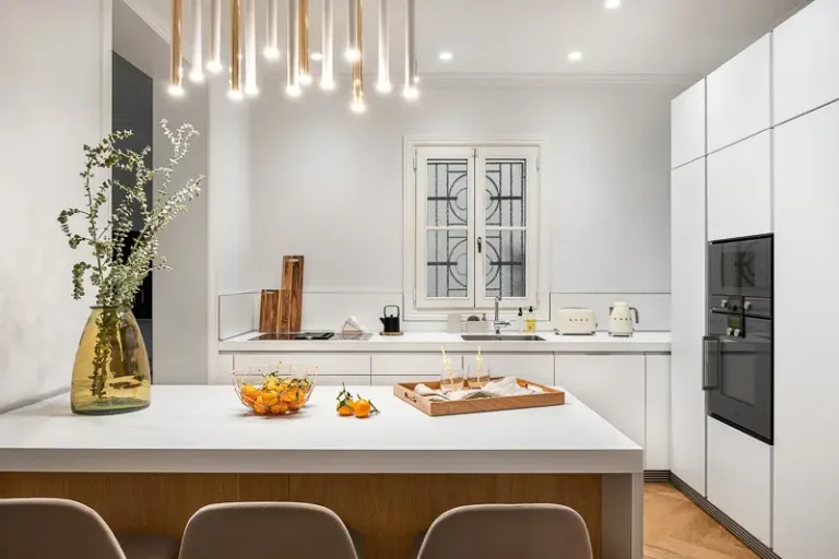 cocina con iluminacion decorativa blanca brillante una isla central con un plato de mandarinas y utensilios de cocina