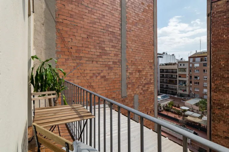un pequeno balcon con una mesa y vistas a las casas de ladrillo