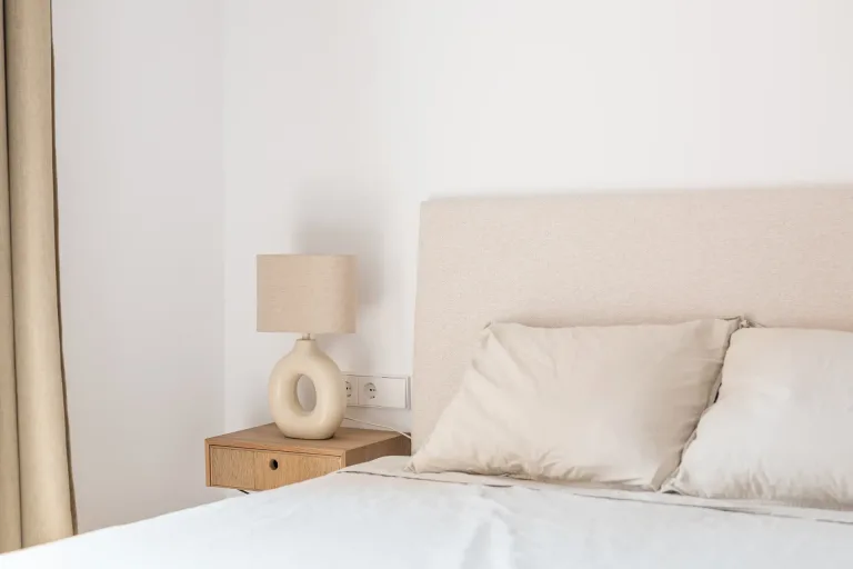 una cama blanca minimalista con un elegante cabecero y almohadas