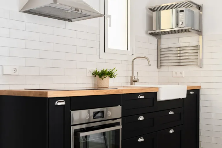 una cocina moderna con elegantes armarios negros y una pared de azulejos blancos