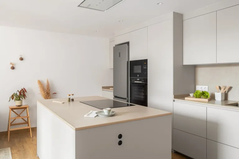 Cocina contemporanea con isla central armarios blancos y electrodomesticos integrados