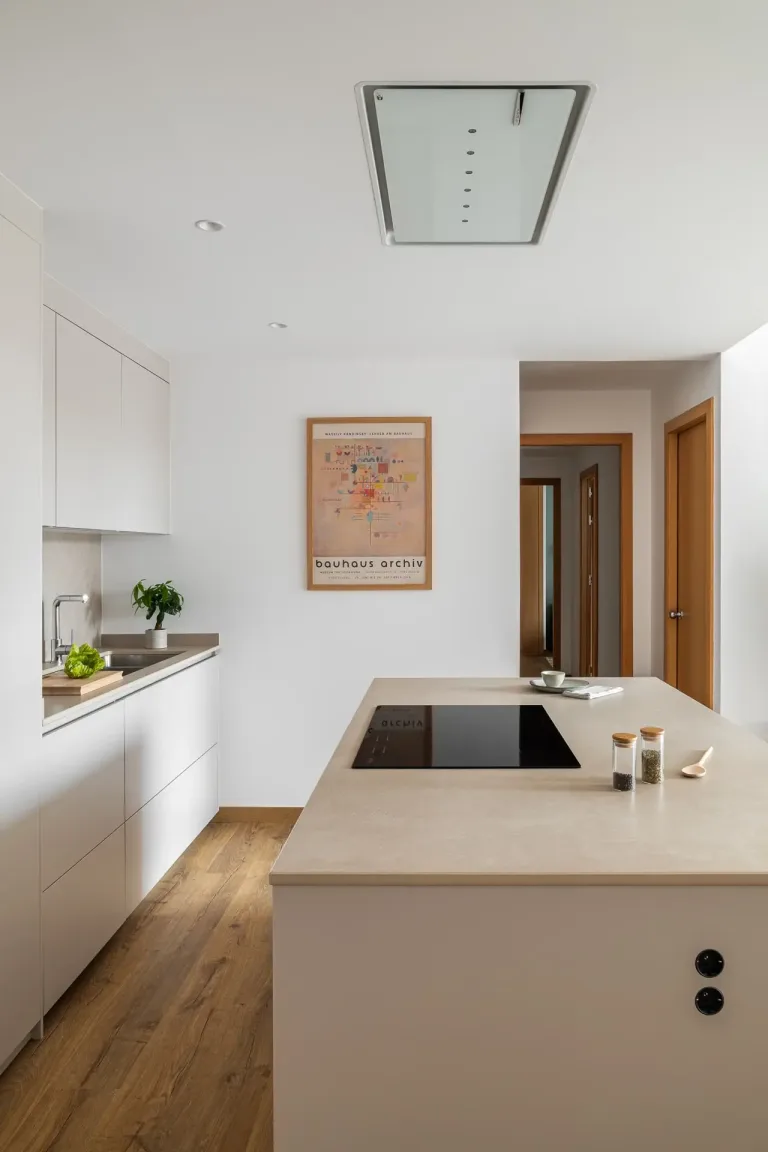 Cocina minimalista con armarios blancos encimera clara y un cuadro en la pared