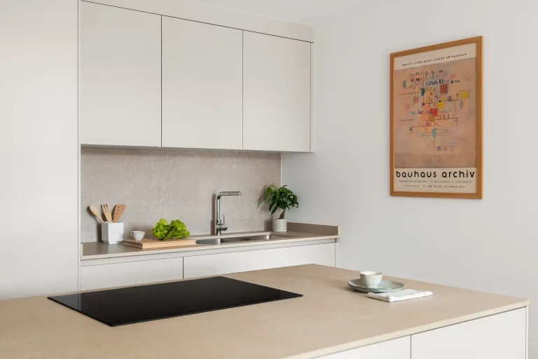 Cocina moderna con encimeras de tono claro grifo plateado y un poster de arte en la pared