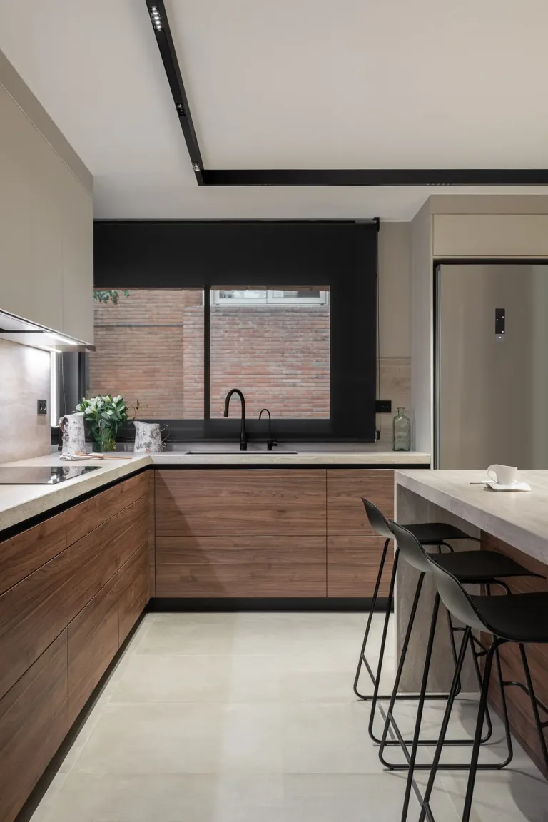 Cocina moderna con gabinetes de madera ventana hacia ladrillo y detalles en tonos suaves