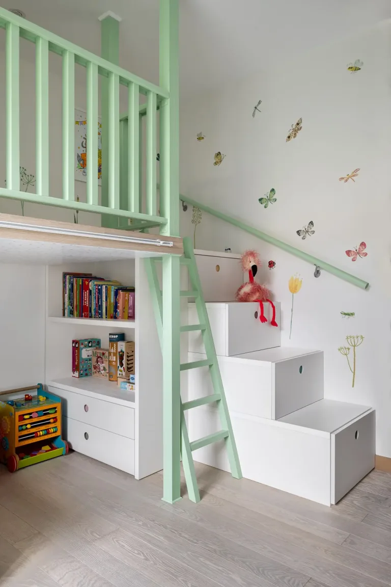 Es un espacio infantil encantador con una estructura de cama elevada en un tono verde pastel