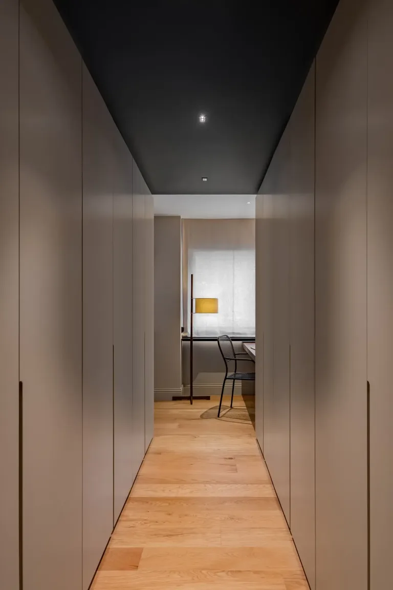 Pasillo elegante con paredes grises techo oscuro y vista a un espacio de trabajo moderno
