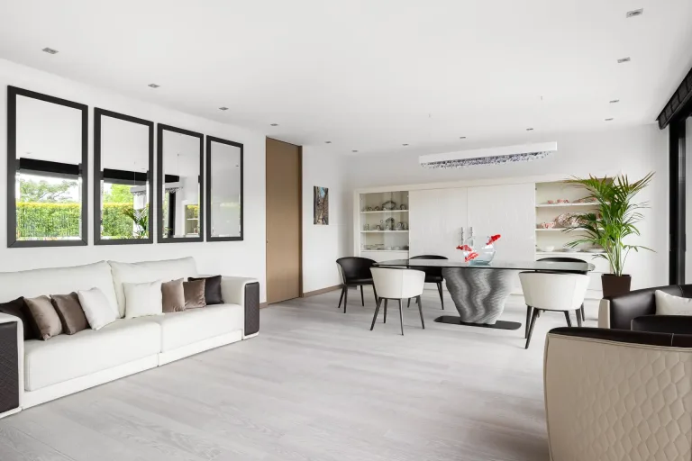 Sala de estar luminosa con muebles modernos y espejos con vista al jardin