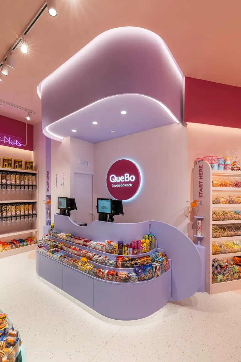 Tienda QueBo Snacks Sweets con mostrador morado y variedad de dulces en estantes min