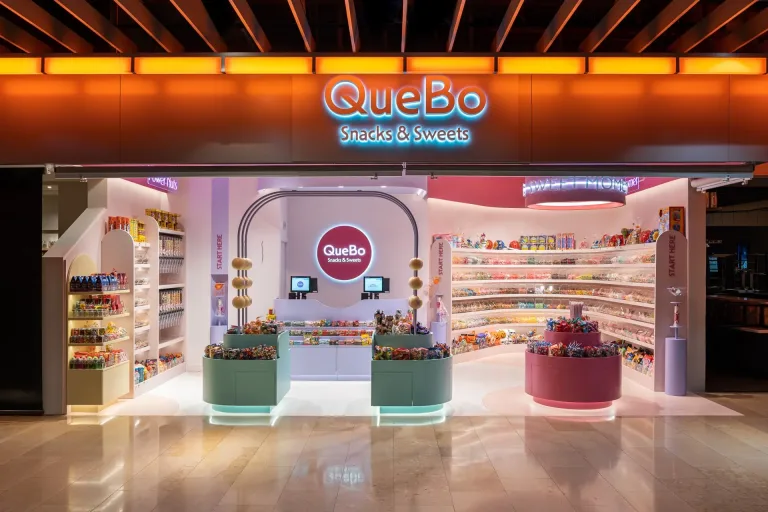 Tienda QueBo Snacks Sweets iluminada ofrece variedad de dulces y snacks en un diseno moderno y colorido min