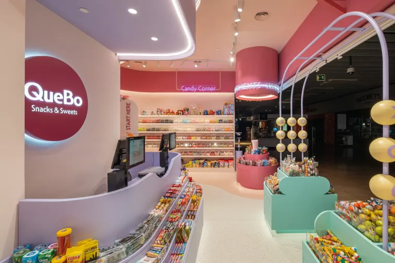 Tienda QueBo de dulces y snacks con mostrador a la izquierda y variedad de caramelos en estantes min