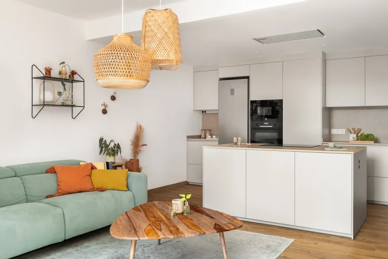 Un espacio de sala moderno con sofa verde claro cojines coloridos y lamparas colgantes tejidas