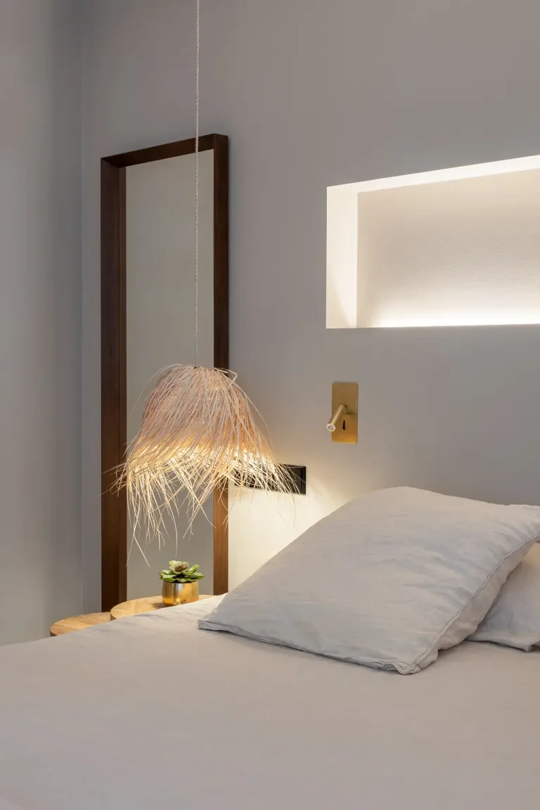 Una lampara de flecos ilumina sutilmente una habitacion de tonos suaves y diseno minimalista