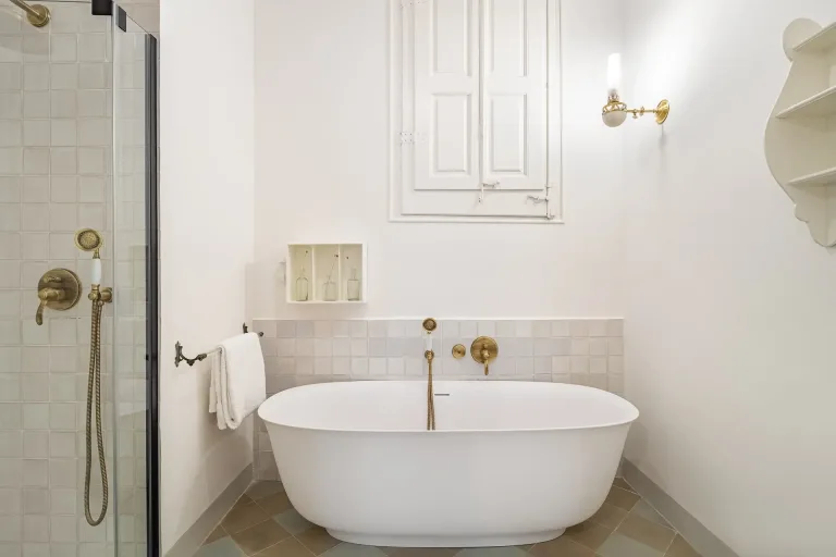 banera en un cuarto de bano con ducha y grifos dorados