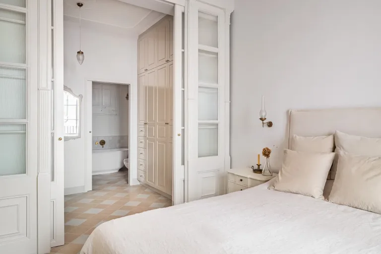 cama con almohadas y una sabana blanca en un dormitorio con vista al bano