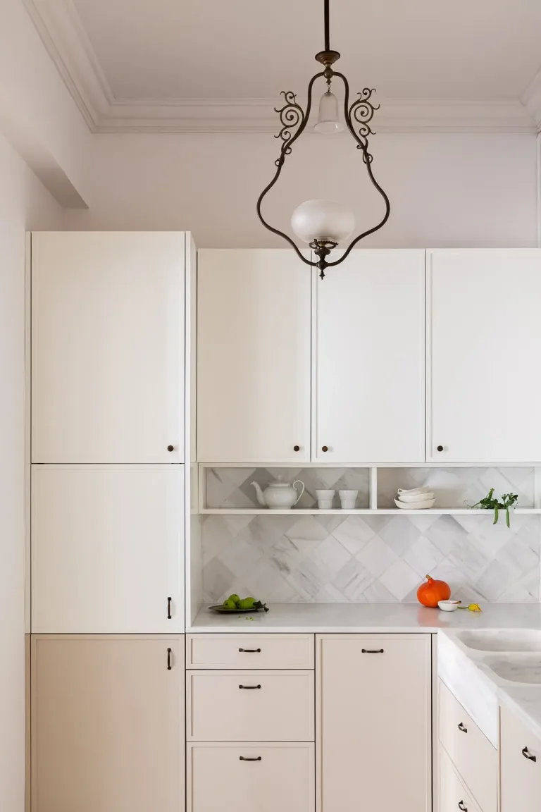 cocina blanca con lampara de arana y fregadero armarios de madera encimeras de marmol