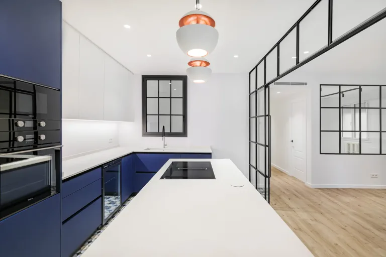cocina con muebles azules y blancos estufa negra y ventanas con marco negro