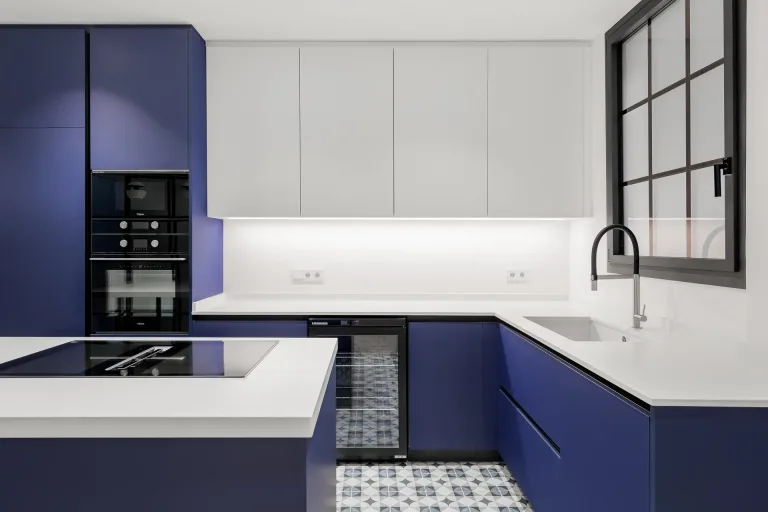 cocina nueva con gabinetes azules y blancos y una estufa negra en la isla de la cocina