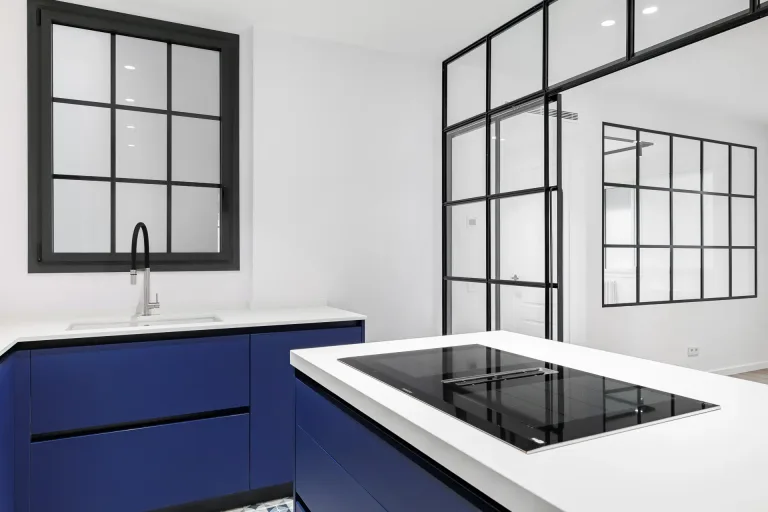 cocina nueva con paredes blancas y muebles azules estufa y fregadero