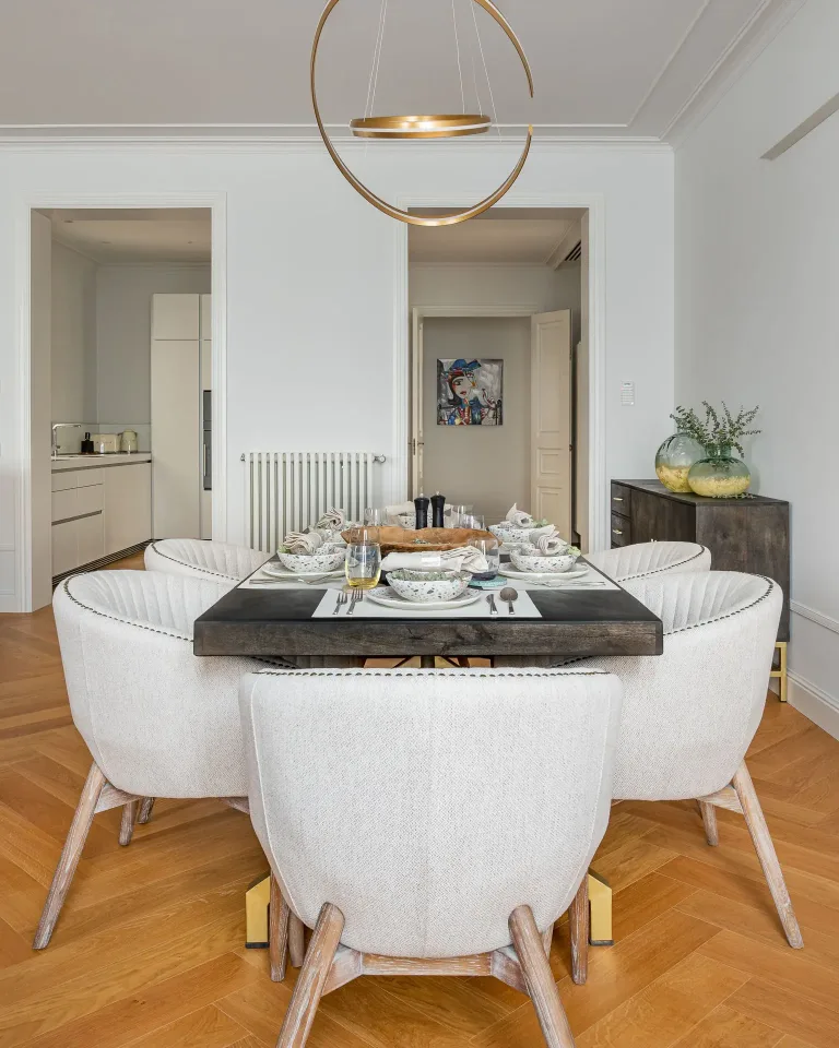 comedor con sillas blancas y una mesa negra en un apartamento moderno