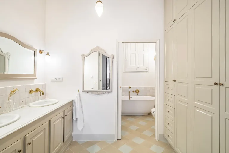 cuarto de bano con lavabo espejo y banera habitacion de color crema