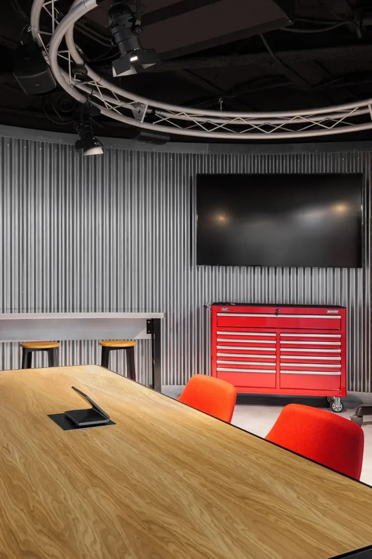 gran mesa de madera con sillas rojas en una sala de reuniones de oficina moderna
