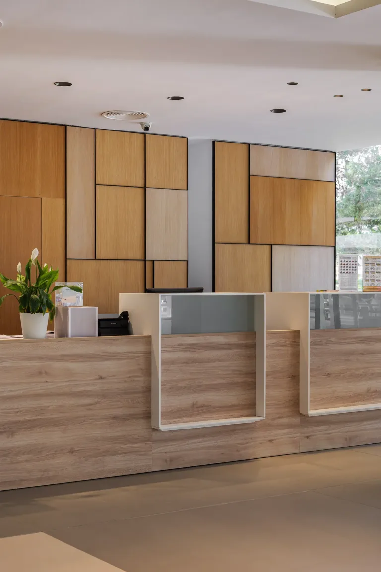 gran mostrador de recepcion de madera de un hotel con una planta paredes de madera paneles de laton