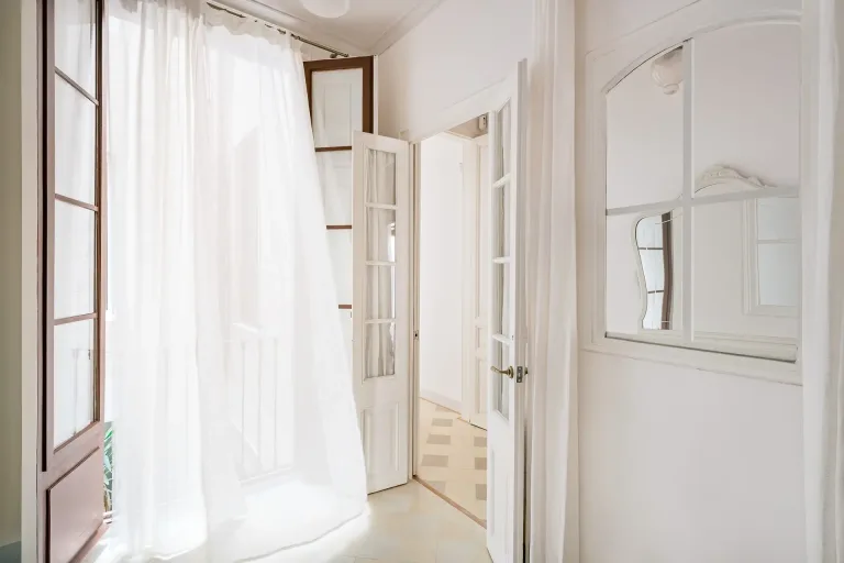 habitacion con puertas abiertas al balcon con una cortina soplada por el viento