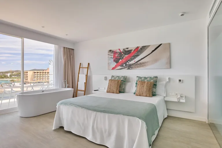 hay una cama con una cubierta blanca y una pintura en la pared fotografia de diseno de interiores