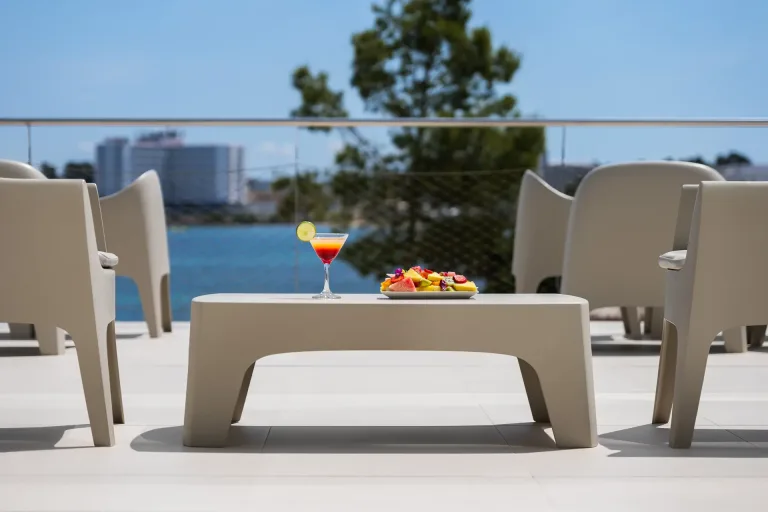 hay una mesa con un plato de fruta y una bebida en la terraza de un hotel muebles de salon ibiza
