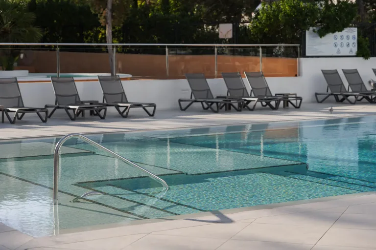junto a la piscina con sillas y mesas y una piscina en primer plano