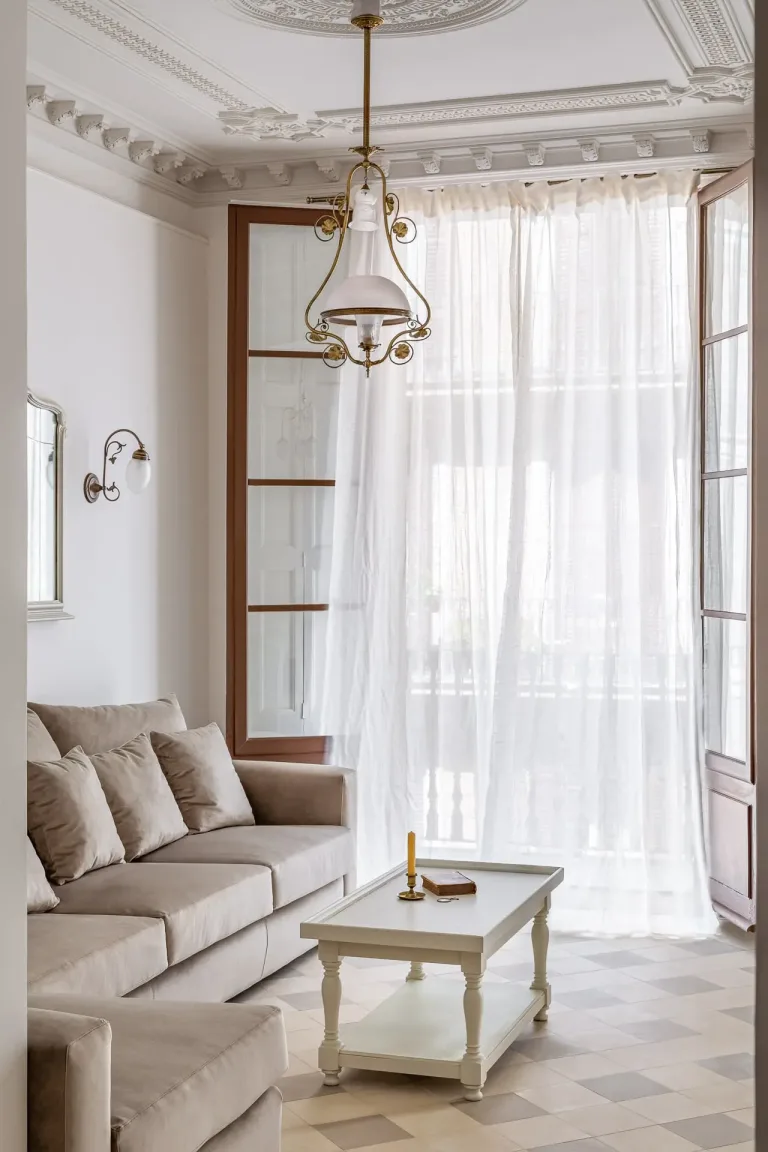 parte de un salon con sofa mesa baja y ventana con cortina de luz luz interior suave