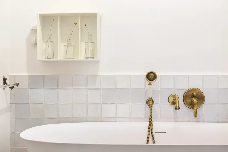 primer plano de una banera blanca con un grifo dorado en un bano clasico