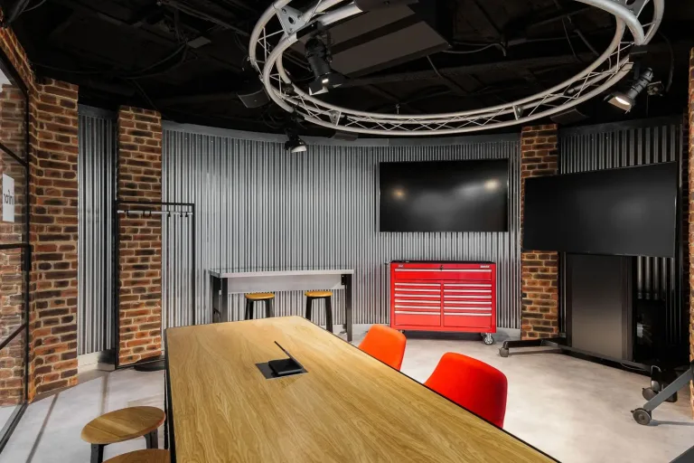sala de reuniones con mesa de madera sillas rojas y televisor para presentaciones