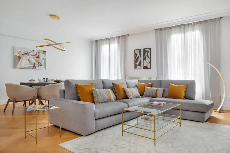 salon con un gran sofa muchas almohadas mesa y alfombra combinacion de colores plata y amarillo