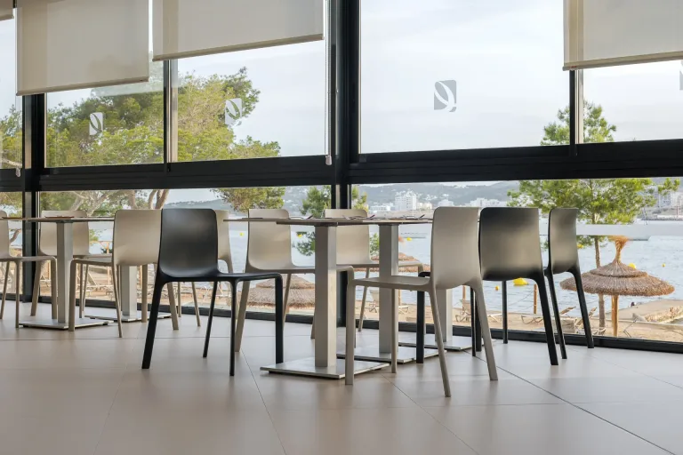 sillas y mesas en un restaurante con vista al mar