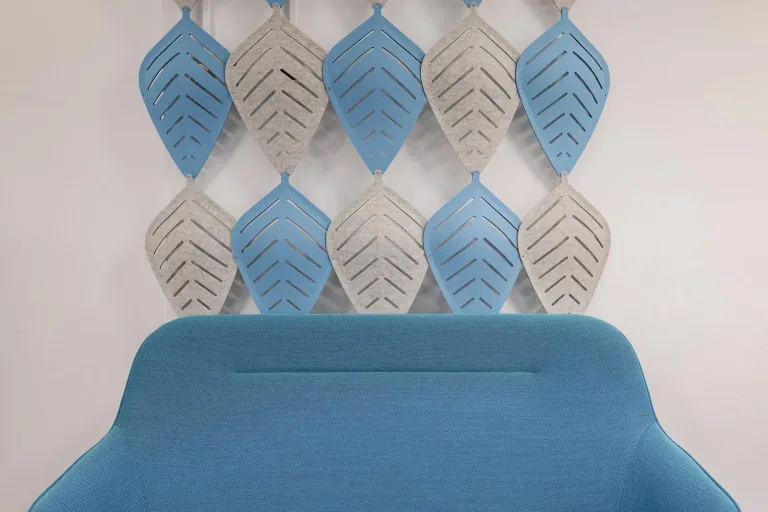 sofa azul en una habitacion con paredes blancas y hojas decorativas hechas de material suave