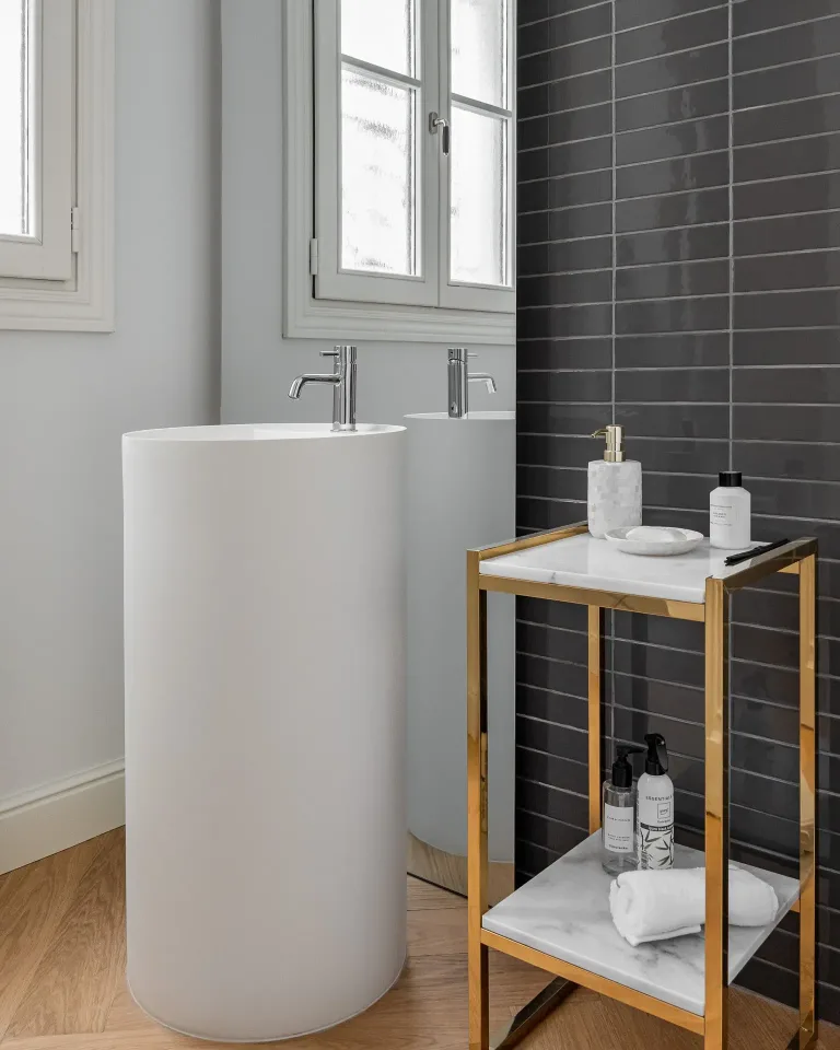 un bano moderno con tubo creativo para lavabo y grifo con paredes de azulejos oscuros