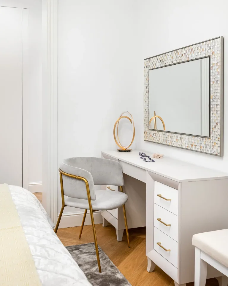 un escritorio blanco con un espejo y una silla en un dormitorio