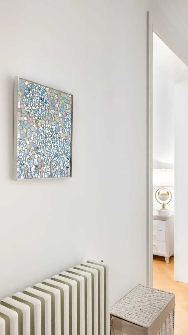 un radiador en un pasillo con un mosaico de vidrio en la pared