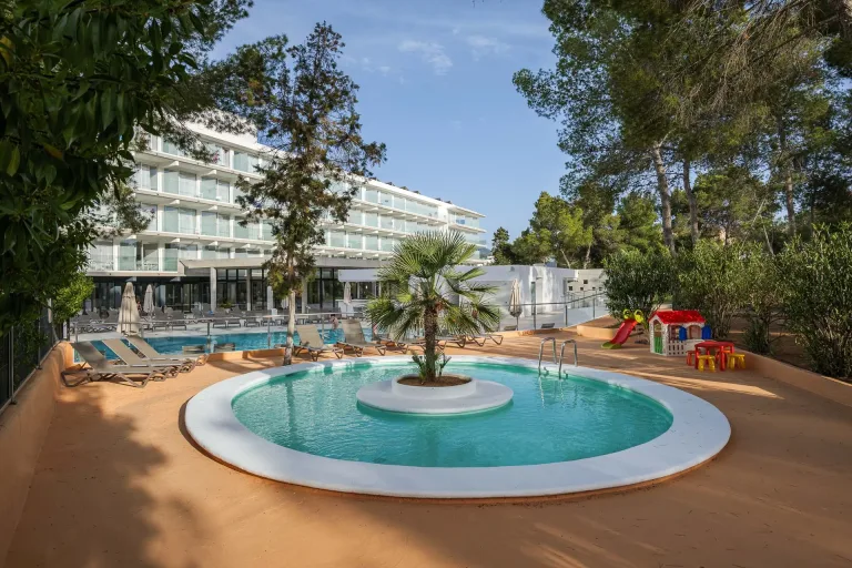 una piscina con una fuente y una palmera en el centro centro vacacional