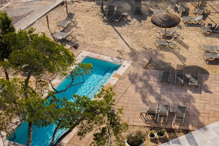 una piscina en medio de una zona hotelera con sillas y sombrillas resort resort de vacaciones en un dia soleado